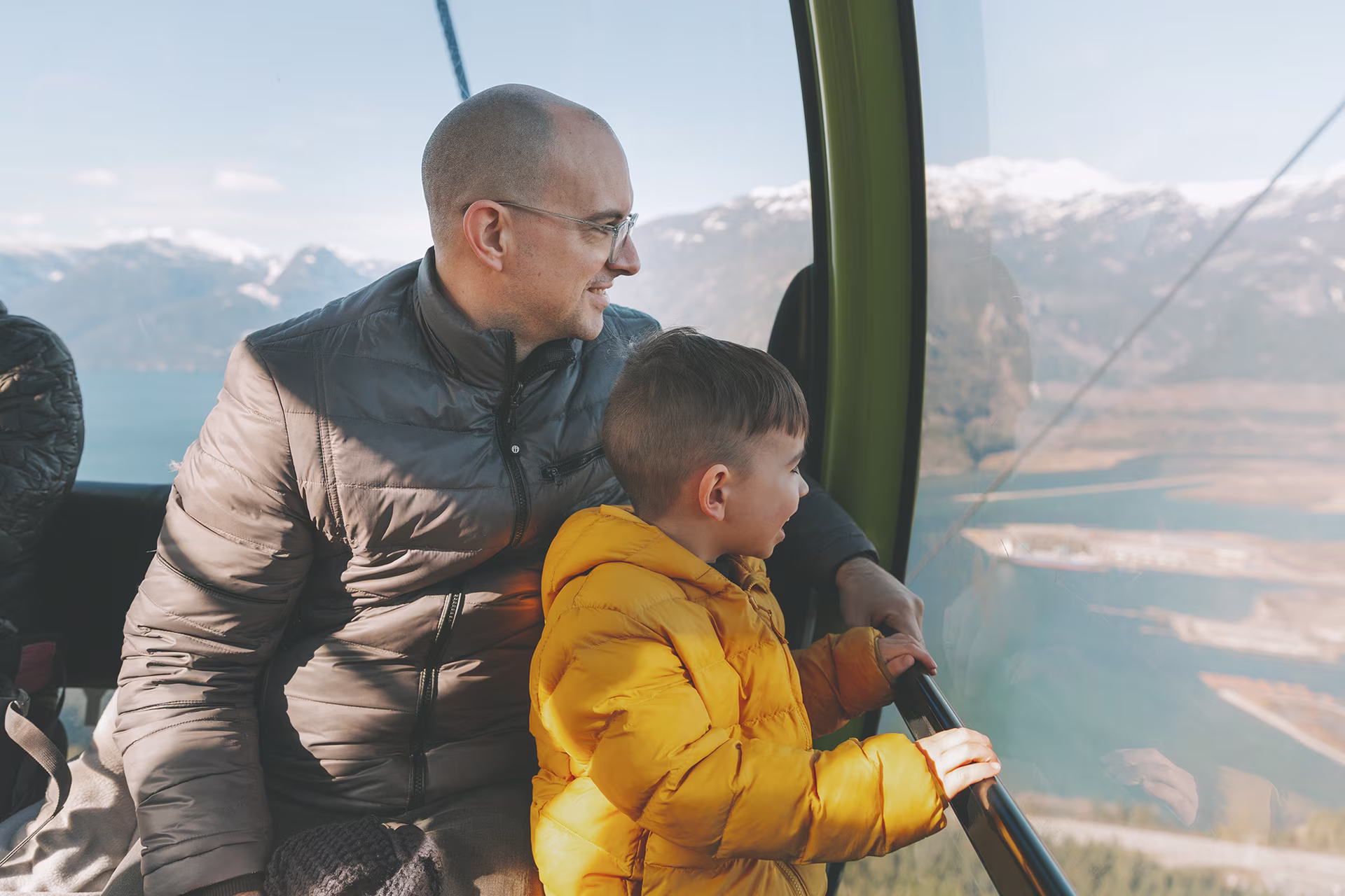 A father and son enjoying the view from a cable car.